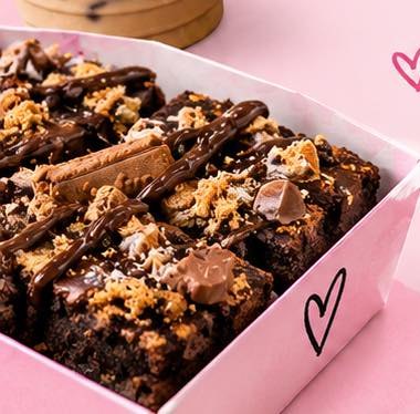 A box of loaded chocolate brownies with chocolate drizzle