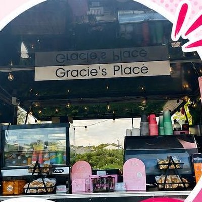 The serving window of the Gracie's Place van, with fairy lights, a Gracie's Place sign, the cabinet and the coffee machine